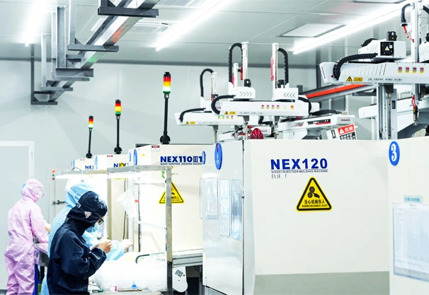 Packson’s certified clean room molding facility featuring a row of NEX110 and NEX120 injection machines, where technicians in full protective apparel manufacture high-precision medical device components.